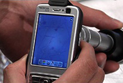 hand holding a cell phone with CellScope clipped to it